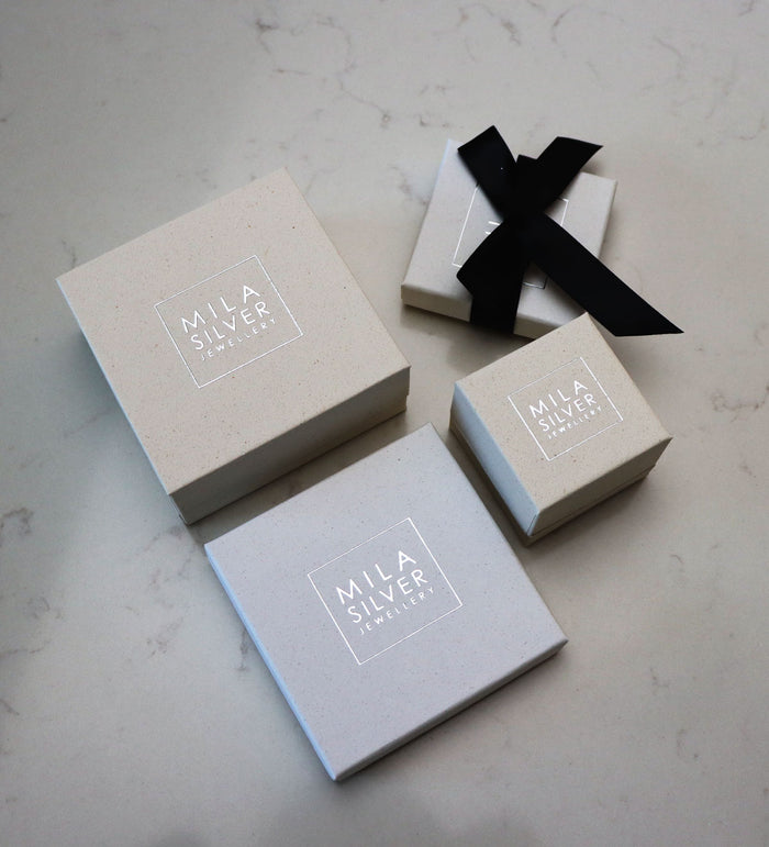 Askar i vita och beiga nyanser med Mila Silver logotyp på i silvertext.