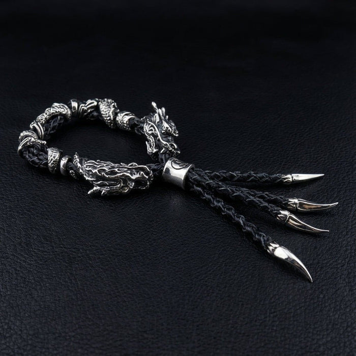 Angled side view of coiled black braided leather bracelet showing fierce silver dragon clasp and four fanning claw pendants