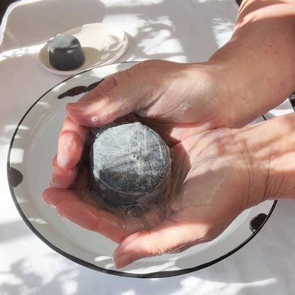 Person lathering JDBotanics oily hair shampoo bar in hands showing rich botanical lather
