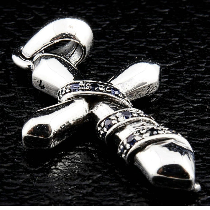 Angled close-up of the polished silver cross, emphasizing the sculpted chain relief and inset blue cubic zirconia stones.