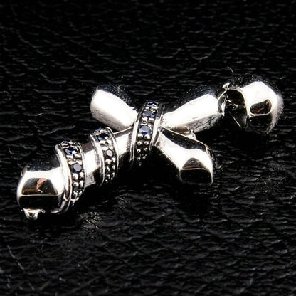 Low angle view of the polished silver cross on black leather, highlighting the prominent bail and blue CZ chain wrap.
