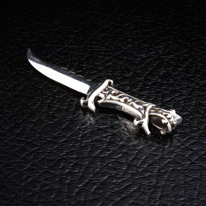 A detail shot of the men's dagger pendant, showing the intricate, oxidized engravings on the sterling silver hilt.