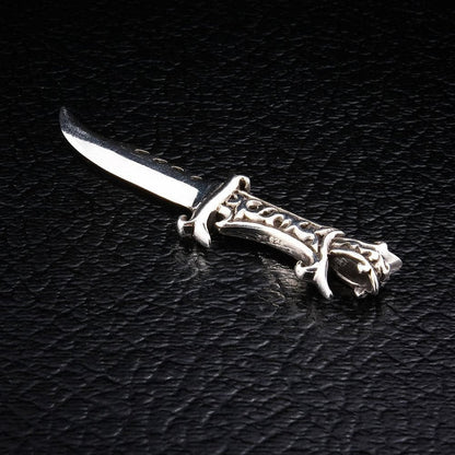 A detail shot of the men's dagger pendant, showing the intricate, oxidized engravings on the sterling silver hilt.