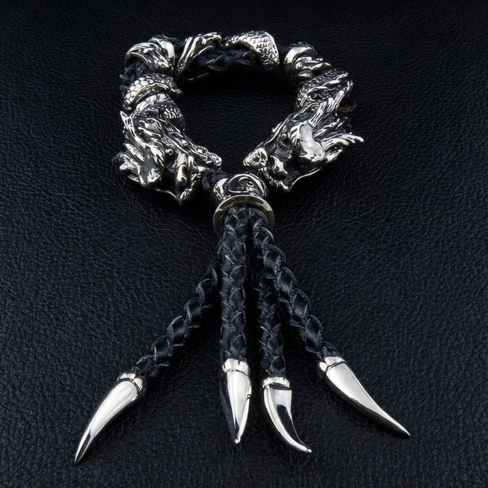Flat lay of braided black leather bracelet with four silver claw pendants and detailed 925 dragon head beads