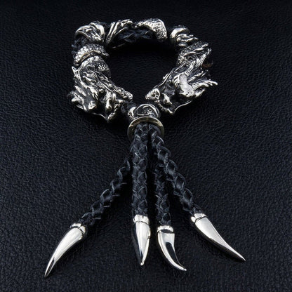 Flat lay of braided black leather bracelet with four silver claw pendants and detailed 925 dragon head beads