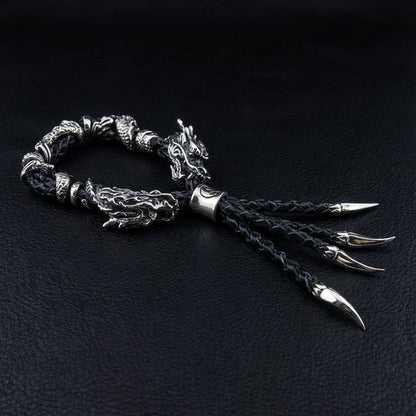 Angled side view of coiled black braided leather bracelet showing fierce silver dragon clasp and four fanning claw pendants