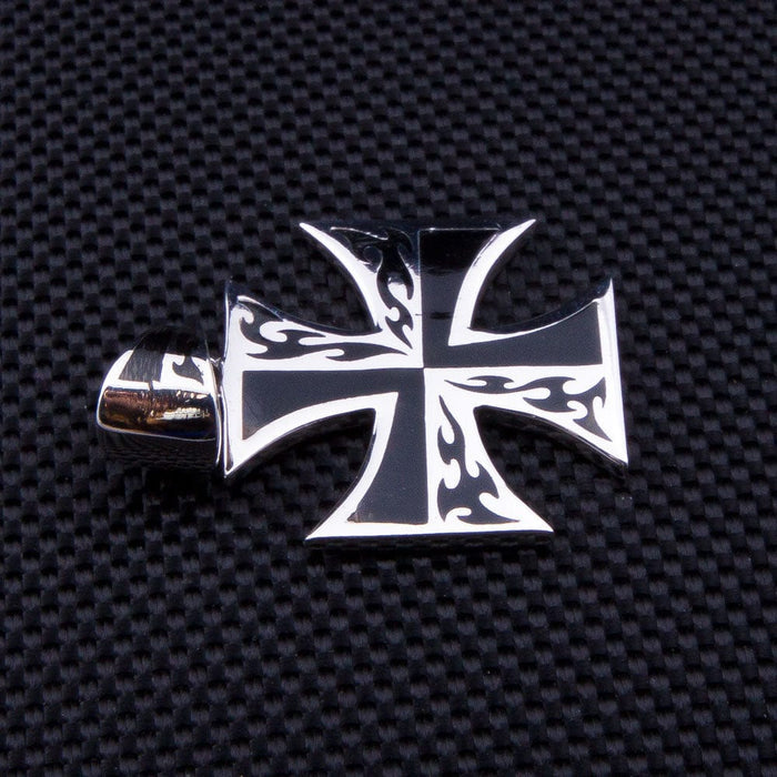 A piece of tattoo-style iron cross jewelry with high-contrast black flames on solid sterling silver.