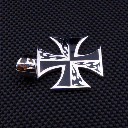 A piece of tattoo-style iron cross jewelry with high-contrast black flames on solid sterling silver.