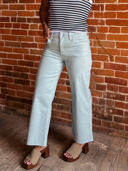 Model wearing wide leg crop jeans in Winter Sky with striped tank and sandals.