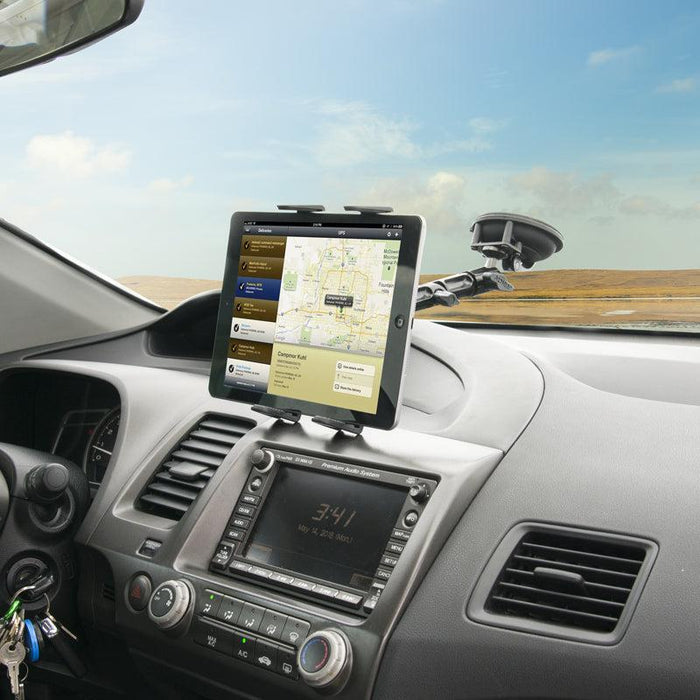 A Heavy-Duty Multi-Angle Slim-Grip® Tablet Suction Mount with 8 Arm secures a tablet displaying a navigation map on a car dashboard. The car interior, ignition keys, and scenic landscape through the windshield are visible.