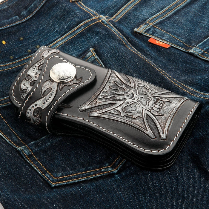A classic long black leather biker wallet with a detailed, hand-carved skull and cross design and a large silver concho.
