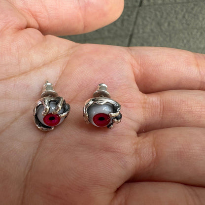 Direct view of vivid red glass eyeball studs, emphasizing the intricate sterling silver claw grips and upright back posts.