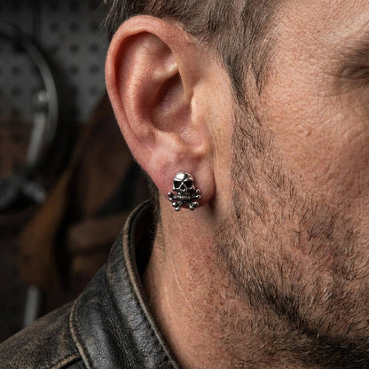 Man wearing silver skull stud earrings showing size and fit on ear