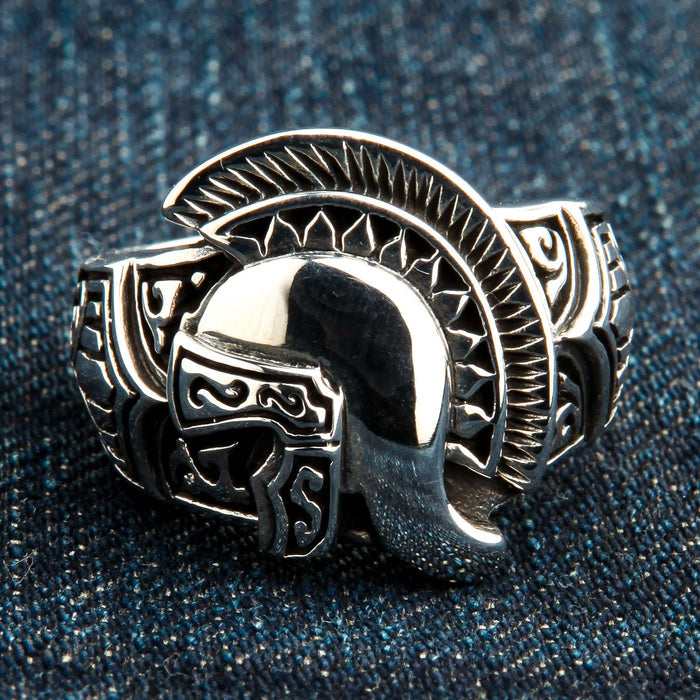 The men's Roman warrior helmet ring resting on a dark denim background.