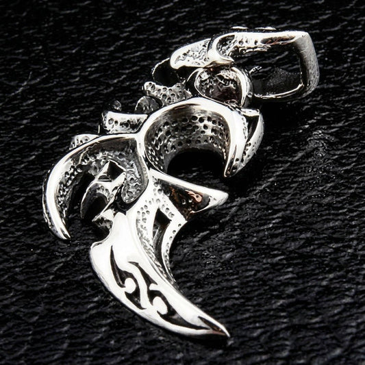 Angled view of the sterling silver carved tribal lines pendant on a dark surface, showing deep grooves and a blade point.