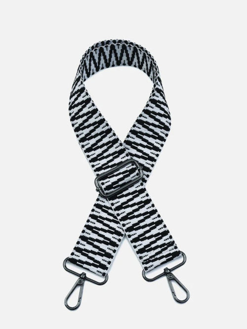 A black and white patterned fabric shoulder strap with a silver metal buckle and two silver carabiner clips, shown against a light gray background.