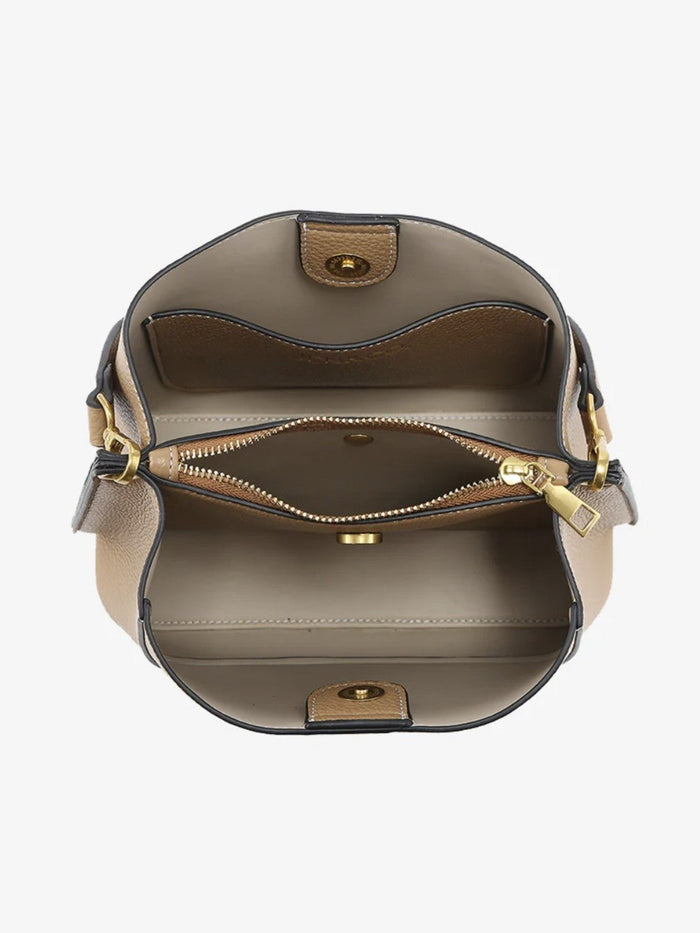 Top-down view of a structured handbag showing its interior, featuring a taupe leather exterior, a beige interior lining, a zippered compartment, and gold-tone hardware.