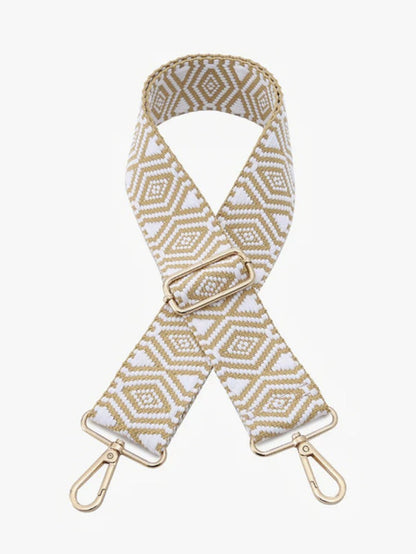 A woven fabric shoulder strap with a geometric diamond pattern in beige and white, featuring gold-tone metal hardware clips and a buckle, shown on a light gray background.