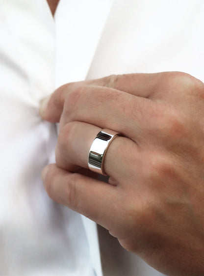 Man som bär en bred silverring med blank slät yta.