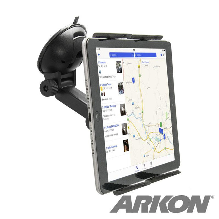 A tablet secured by the Windshield Suction Tablet Mount with Extension Arm in landscape mode displays a map app. The universal holder attaches to the black mount on the car windshield, and the ARKON logo appears in the lower right corner.