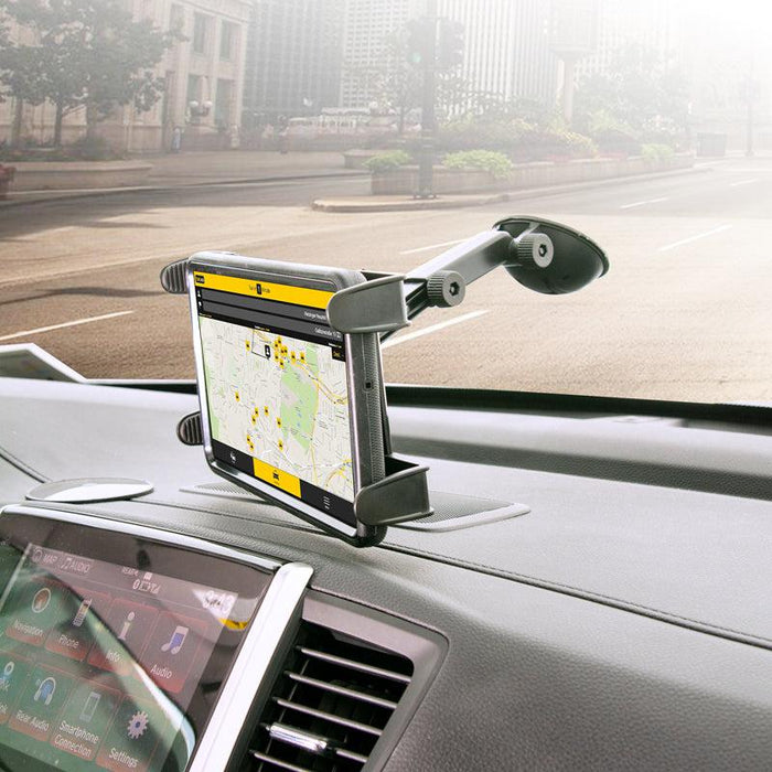 A GPS tablet secured with the Windshield Suction Tablet Mount with Extension Arm displays a city map and directions. Sunlight streams through the windshield, revealing city buildings outside.